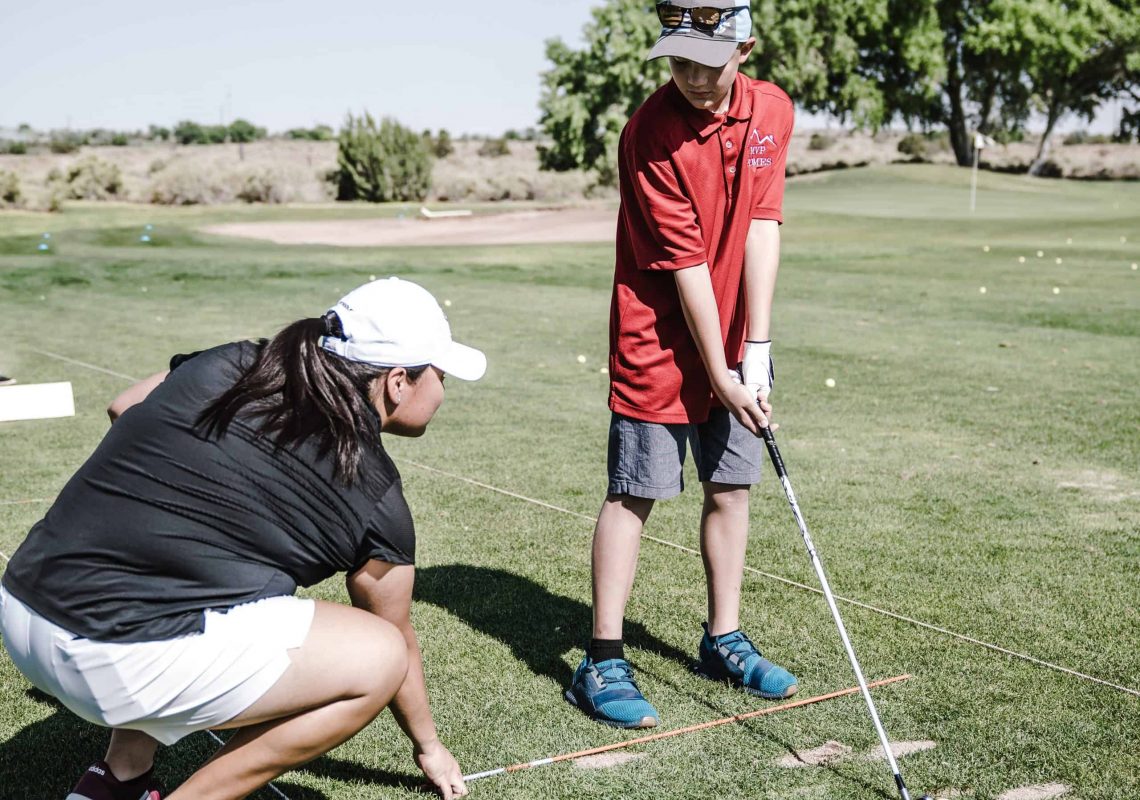 boy-holding-golf-club-in-front-of-crouching-woman-1325655